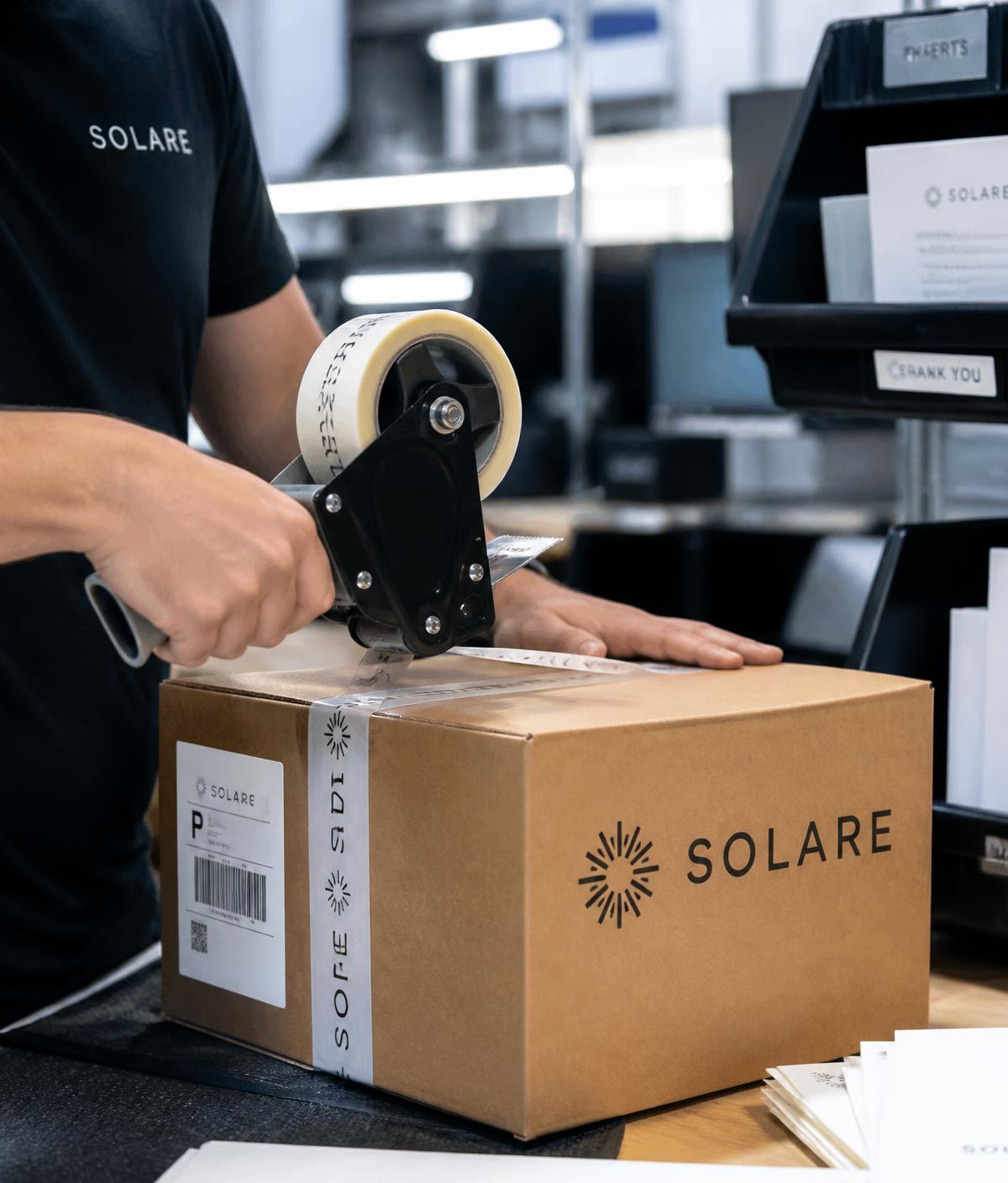 Team member sealing a branded shipping box at a packing station